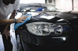 A man cleaning car with microfiber cloth, car detailing (or valeting) concept. Selective focus.