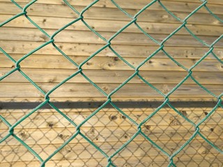 a green metal mesh, an industrial wall with some ripples and screws. Rusty, painted in green and with bubbles on the painting.The wooden wall