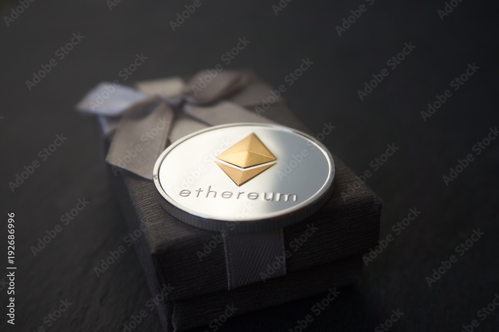 Silver Ethereum coin lying on the grey gift box