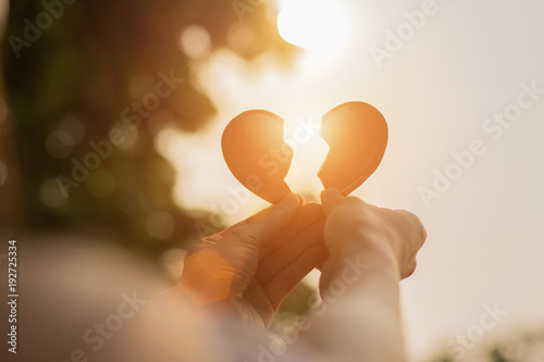 Fotomural Silhouette broken heart,close up woman hand holding broken heart in the park