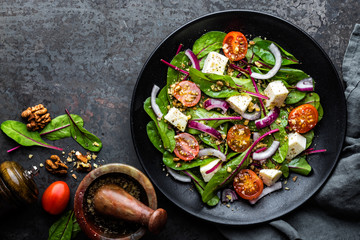 plate of nutritious simple salad with chard, walnuts, soft cheese, onions and oil, top view, space for text