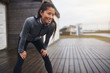 © Flamingo Images - Smiling Asian woman catching her breathe while out jogging