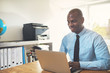 © Flamingo Images - Smiling African businessman working on a laptop in an office
