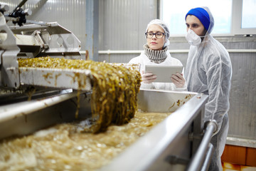 Control seafood factory staff in uniform standing by working industrial machine