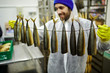 © pressmaster - Appetizing smoked mackerels hanging on wire held by man in uniform