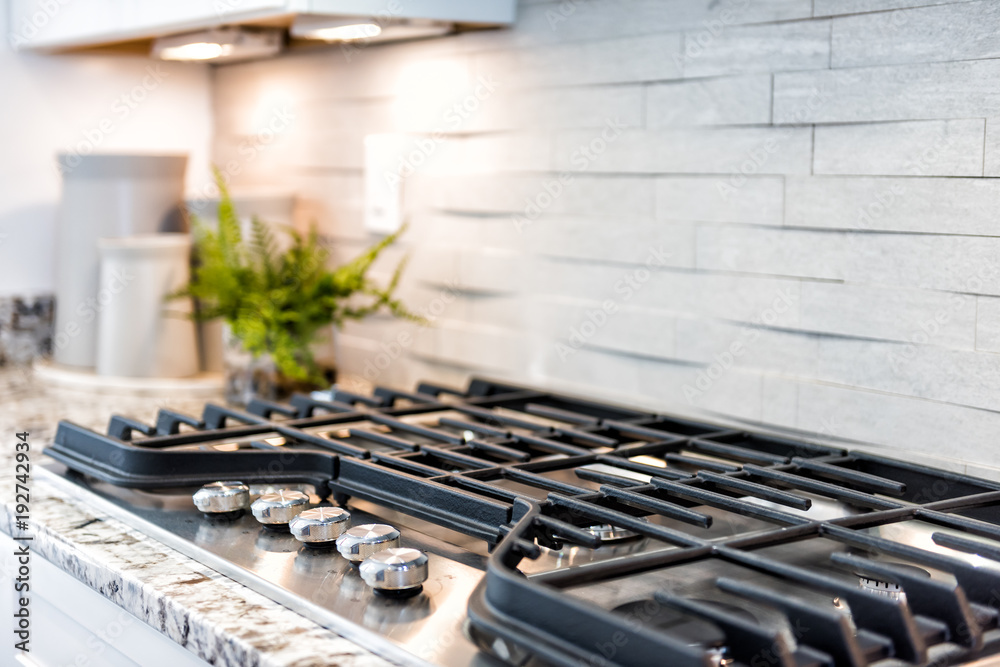 Macro closeup of modern luxury gas stove top with tiled backsplash