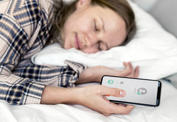 Wall Mural - Caucasian woman sleeping in bed with mobile phone in hand