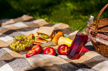 Picnic In Nature. In The Park Or Garden. Grapes Apples Sandwiches With Wine Or Juice. Basket With Food. Picnic Blanket.