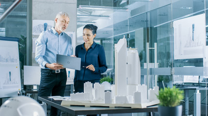 Aufkleber - Male Senior Engineer Holds Laptop and has Discussion with Female Chief Engineer. They Work on a Building Model for a New District Urban Planning Project.