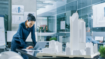 Aufkleber - Female Architectural Designer Works on a Laptop,  Engineering New Building Model for the Urban Planning Project. Clean Minimalistic Office, Concrete Walls Covered by Blueprints and Documents.