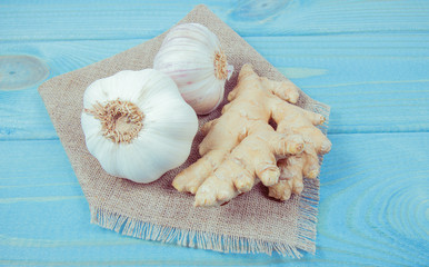 Garlic bulbs with ginger on blue wooden table. Concept of natural medicine.