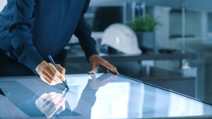 Aufkleber - Talented Young Female Architectural Designer Draws Building Concept on a Graphics Tablet Display Vertical Touchscreen Table. Clean Minimalistic Office, Concrete Walls Covered by Blueprints.