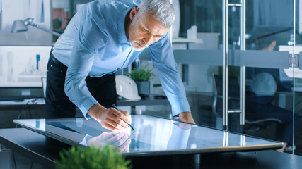 Aufkleber - Senior Architectural Engineer Draws Building Concept on a Graphics Tablet Display Vertical Touchscreen Table. Clean Minimalistic Office, Concrete Walls Covered by Blueprints.