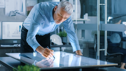 Aufkleber - Senior Architectural Engineer Draws Building Concept on a Graphics Tablet Display Vertical Touchscreen Table. Clean Minimalistic Office, Concrete Walls Covered by Blueprints.