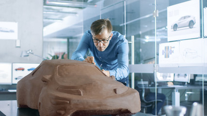 Aufkleber - Experience Automotive Designer with a Rake Sculpts Prototype Car Model from Plasticine Clay. He Works in a Modern Studio in a Major Automotive Company's Headquarters.