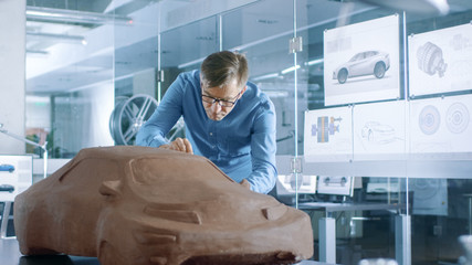 Aufkleber - Experience Automotive Designer with a Rake Sculpts Prototype Car Model from Plasticine Clay. He Works in a Modern Studio in a Major Automotive Company's Headquarters.