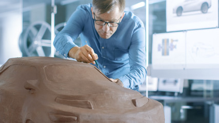 Aufkleber - Experience Automotive Designer with a Rake Sculpts Prototype Car Model from Plasticine Clay. He Works in a Modern Studio in a Major Automotive Company's Headquarters.