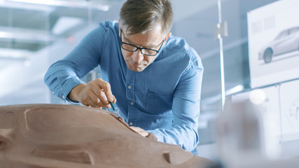 Aufkleber - Experience Automotive Designer with a Rake Sculpts Prototype Car Model from Plasticine Clay. He Works in a Modern Studio in a Major Automotive Company's Headquarters.