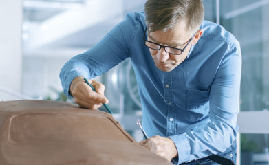 Aufkleber - Experience Automotive Designer with a Rake Sculpts Prototype Car Model from Plasticine Clay. He Works in a Modern Studio in a Major Automotive Company's Headquarters.