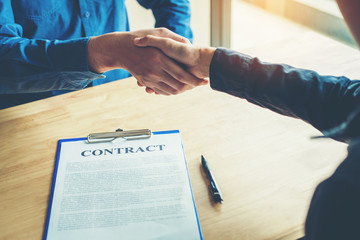 Business people negotiating a contract handshake between two colleagues