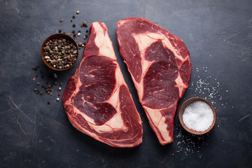 Poster - Raw fresh marbled meat Steak Ribeye Black Angus on black marble background. Beef with spices on a dark stone table. Top view