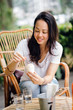 © Danon - Young and attractive Pan Asian woman enjoying an ice cream in the sun on a weekend in a cafe outdoors. She is smiling and looking at the ice cream.