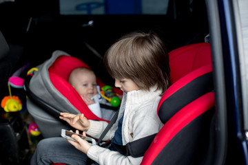 Wall Mural - Little baby boy and his older brother, traveling in car seats, going on a holiday