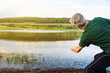 © creativefamily - Senior man playing stone skipping at a lake