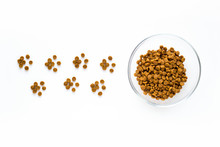 Paw Sign Made Of Dry Cat Or Dog Food With Full Bowl. Pet Care And Veterinary Concept With Letters On White Background.