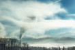 Dampf steigt aus Rauchfang von Industrieanlage mit dramatischer Lichtstimmung