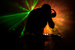 © zef art - DJ Spinning, Mixing, and Scratching in a Night Club, Hands of dj tweak various track controls on dj's deck, strobe lights and fog, or Dj mixes the track in the nightclub at party