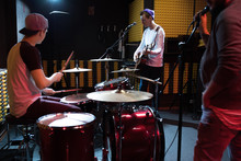 Band Of Young Musicians Performing In Dim Recording Studio Making New Album, Drum Set In Foreground