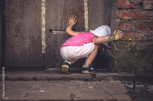 Fotografía Curious child lookinginto dark hole in barn door in countryside shed concept cur