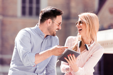 Wall Mural - Happy couple having good time in the city with tablet.