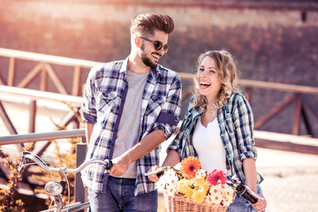 Wall Mural - Happy young couple walking in the bridge with a bicycle.