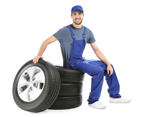 Wall Mural - Young mechanic in uniform with car tires on white background