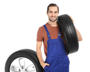 Wall Mural - Young mechanic in uniform with car tires on white background