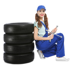 Wall Mural - Young mechanic in uniform with car tires on white background