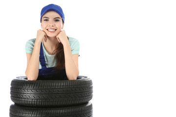 Wall Mural - Young mechanic in uniform with car tires on white background