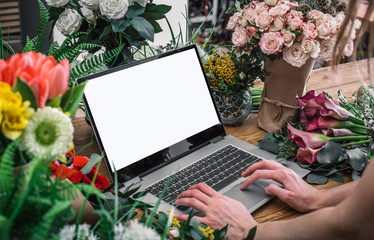 Florist using laptop with blank screen with flowers bouquet