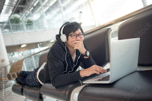Young Asian Man Using Laptop Computer And Listening To Music While