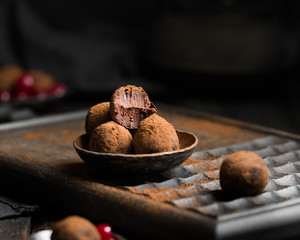 Chocolate truffle. Dark chocolate and cherry candy sprinkled with cocoa on a dark wooden background in rustic style. Atmospheric food photo.  Homemade fresh energy balls.