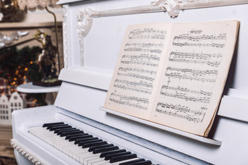 white piano with book with notes on it