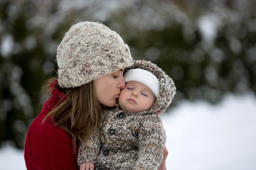 Poster - Beautiful mother and cute baby boy in knitted onesie, having taken their beautiful winter outdoor portrait