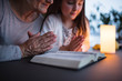 © Halfpoint - A small girl and grandmother praying at home.