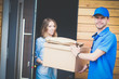 © lenets_tan - Smiling delivery man in blue uniform delivering parcel box to recipient - courier service concept. Smiling delivery man in blue uniform