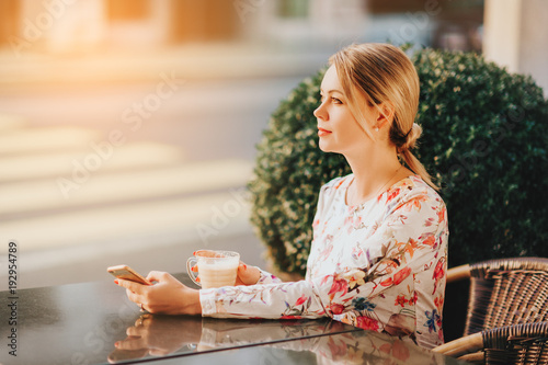 Poster Outdoor portrait of beautiful woman resting in cafe with cup of coffee
