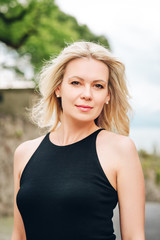 Wall Mural - outdoor portrait of young blond woman wearing black dress