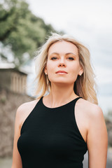 Wall Mural - outdoor portrait of young blond woman wearing black dress