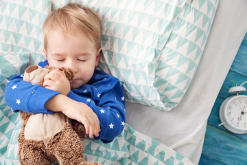 Wall Mural - three years old child sleeping in bed with alarm clock